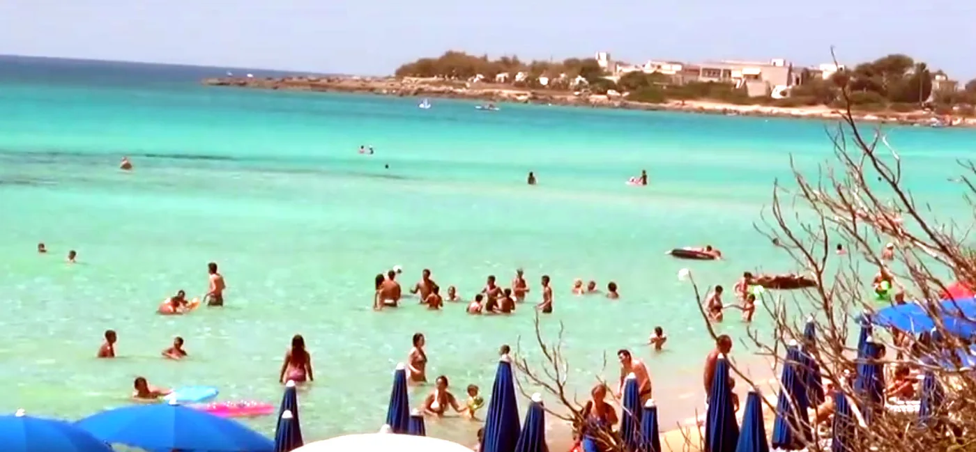 Türkisfarbenes Meer und Badegäste am Strand von Punta Prosciutto.